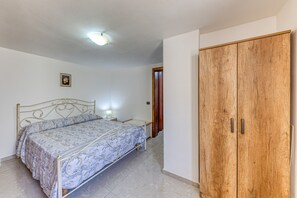 Une chambre à coucher comprenant un lit, une table de chevet, une lampe, une armoire et un luminaire au plafond.