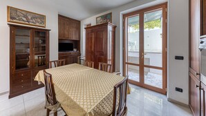 A dining area with a table, chairs, wooden cabinets, and a television. - Apartment "Casa di Marika" with Private Terrace and Air Conditioning (marina di leuca)