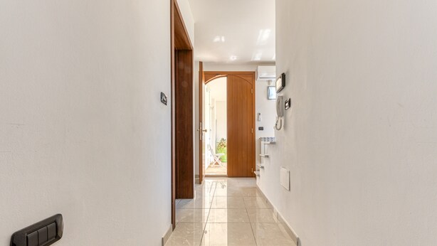 A hallway with a wooden door, a light switch, and a phone on the wall. - Apartment "Casa di Marika" with Private Terrace and Air Conditioning (marina di leuca)