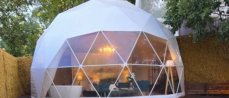 Estructura en forma de domo geodésico con un jacuzzi en primer plano.
