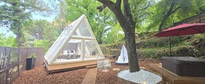 Una zona relax esterna accogliente con una struttura in vetro triangolare, una sedia a dondolo e un modellino di barca a vela.
