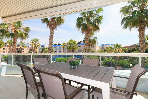 A terrace with a table and chairs, overlooking a cityscape with palm trees and buildings.