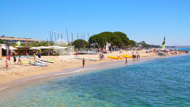 A beach with clear blue water, a sandy shore, and several boats.