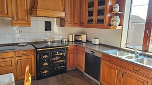 Una cocina con armarios de madera, estufa negra, lavavajillas y ventana con vistas.