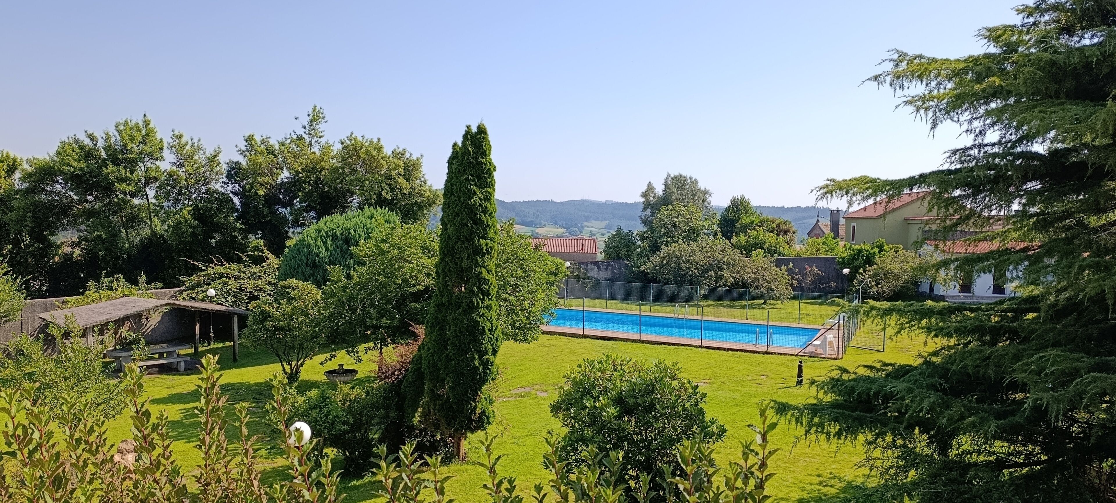 A swimming pool surrounded by lush greenery and a view of distant hills.