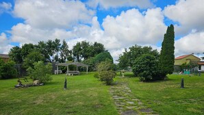 Un espacio al aire libre con césped, un sendero de piedra, un pabellón y varios árboles.