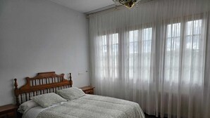 Un dormitorio con cama de madera, cortinas blancas y una araña.
