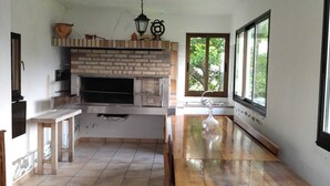 Una cocina con chimenea de ladrillo, mesa de madera y ventanas amplias.