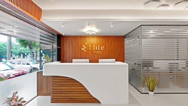 A reception desk with a wooden panel wall and a sign that reads "The Elite Hotel." - The Elite Hotel  (Hyderabad)