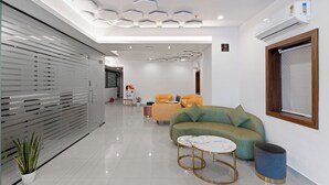 A modern living room with a sofa, two side tables, and a potted plant. - The Elite Hotel  (Hyderabad)