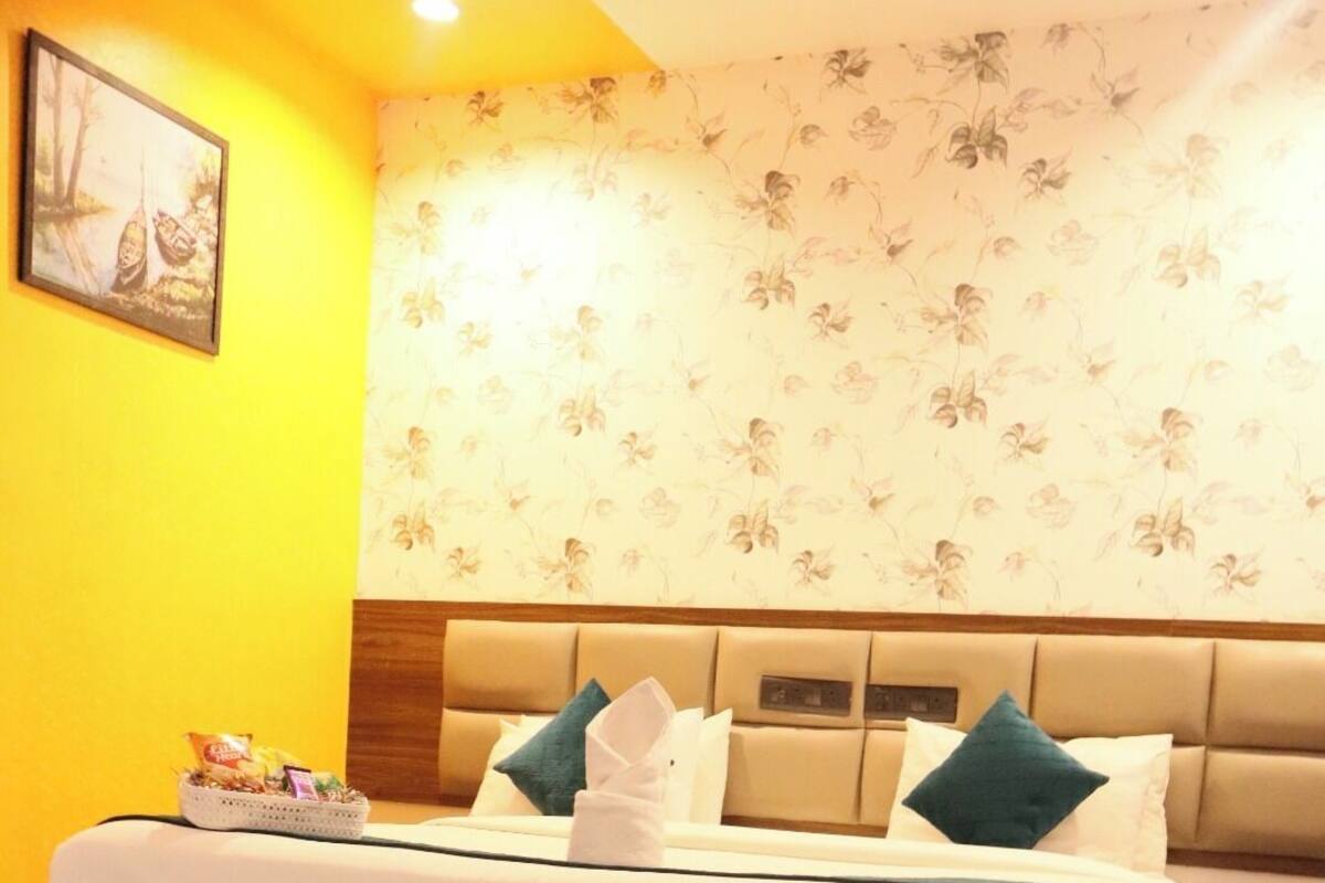A hotel room with a large bed, a headboard with a clock, and a floral wallpaper.