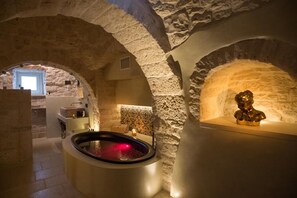 A spa area with a stone-walled room, a hot tub, and a statue.