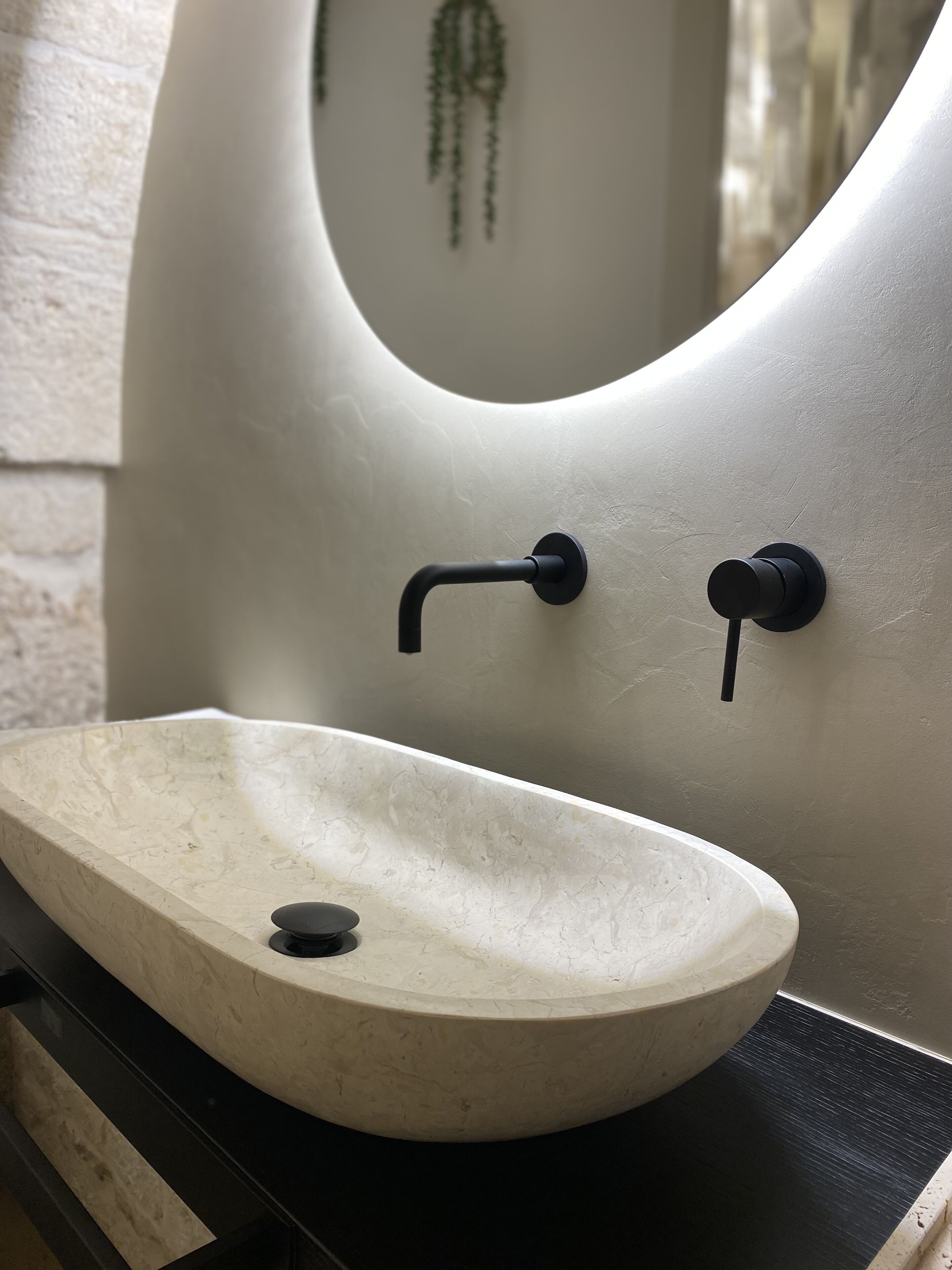 Une salle de bain avec un lavabo blanc, un miroir et un robinet noir.