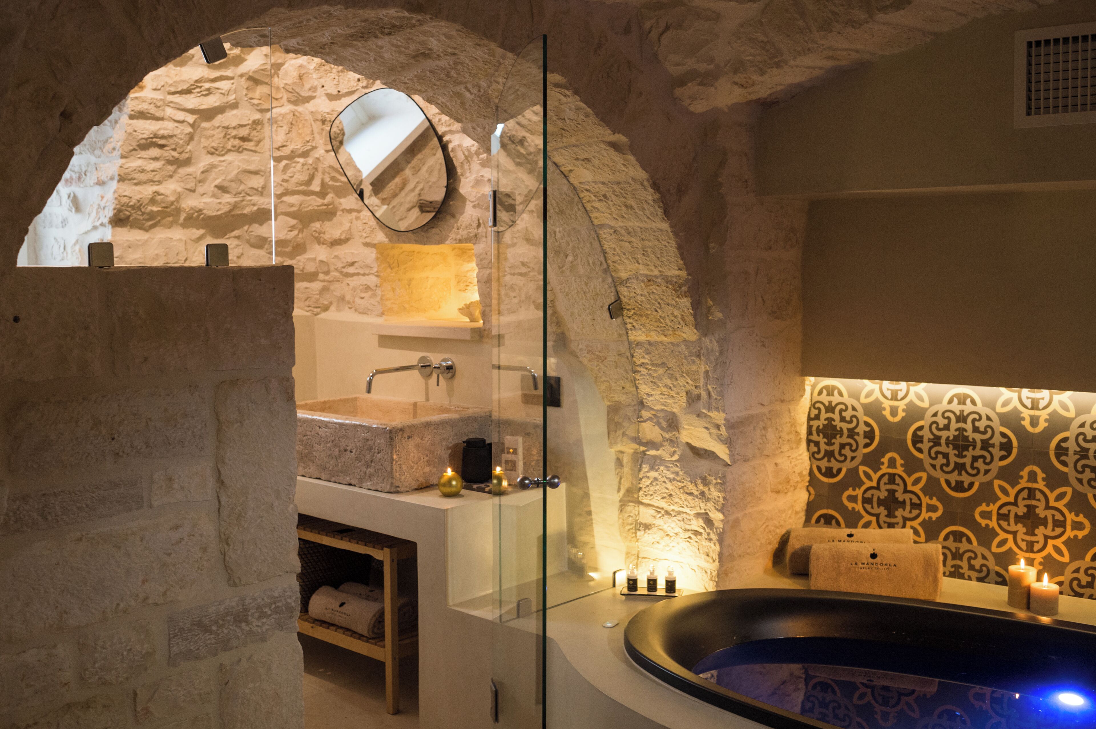 Ein modernes Badezimmer mit Bogen aus Stein, einer freistehenden Badewanne und einer in Glas eingefassten Duschkabine.