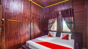 A wooden-paneled room with a bed, a bench, and a window with curtains. - Hotel O Filadelfia Resto & Penginapan Near Benteng Moraya (Manado)