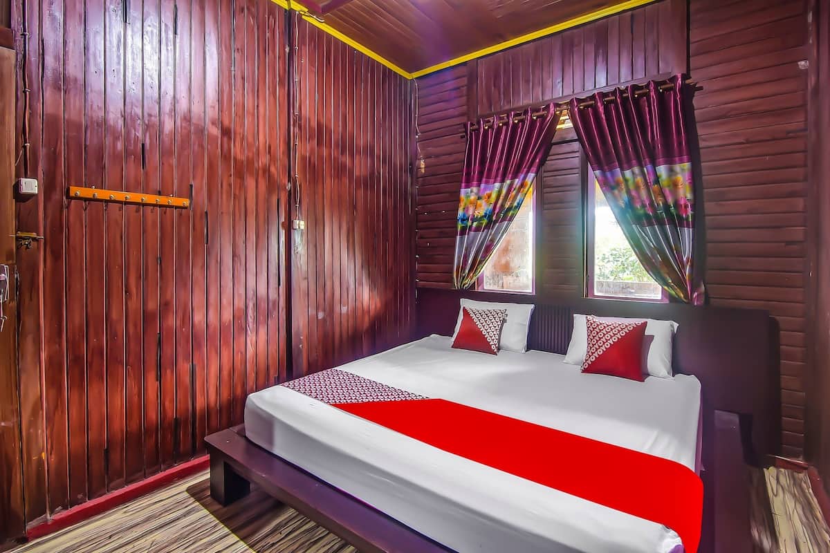 Una stanza con rivestimenti in legno, un letto, una panca e una finestra con tende.