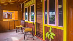 A wooden room with a yellow and pink color scheme, featuring two chairs and a window with a view of greenery outside. - Hotel O Filadelfia Resto & Penginapan Near Benteng Moraya (Manado)
