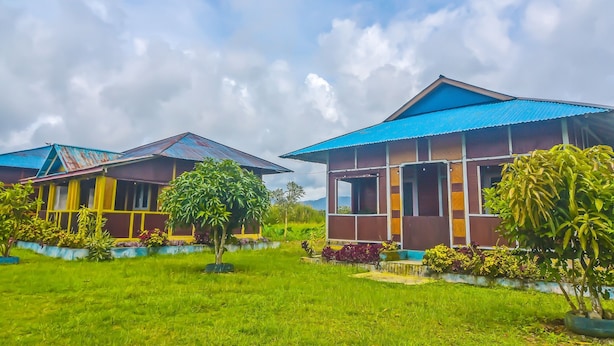 A row of two-story buildings with blue roofs, surrounded by well-maintained lawns and various plants. - Hotel O Filadelfia Resto & Penginapan Near Benteng Moraya (Manado)