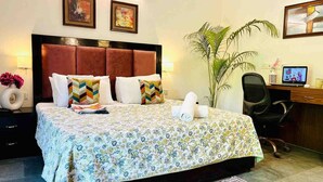 Habitación de hotel con una cama grande, un escritorio, una silla y una planta en maceta.