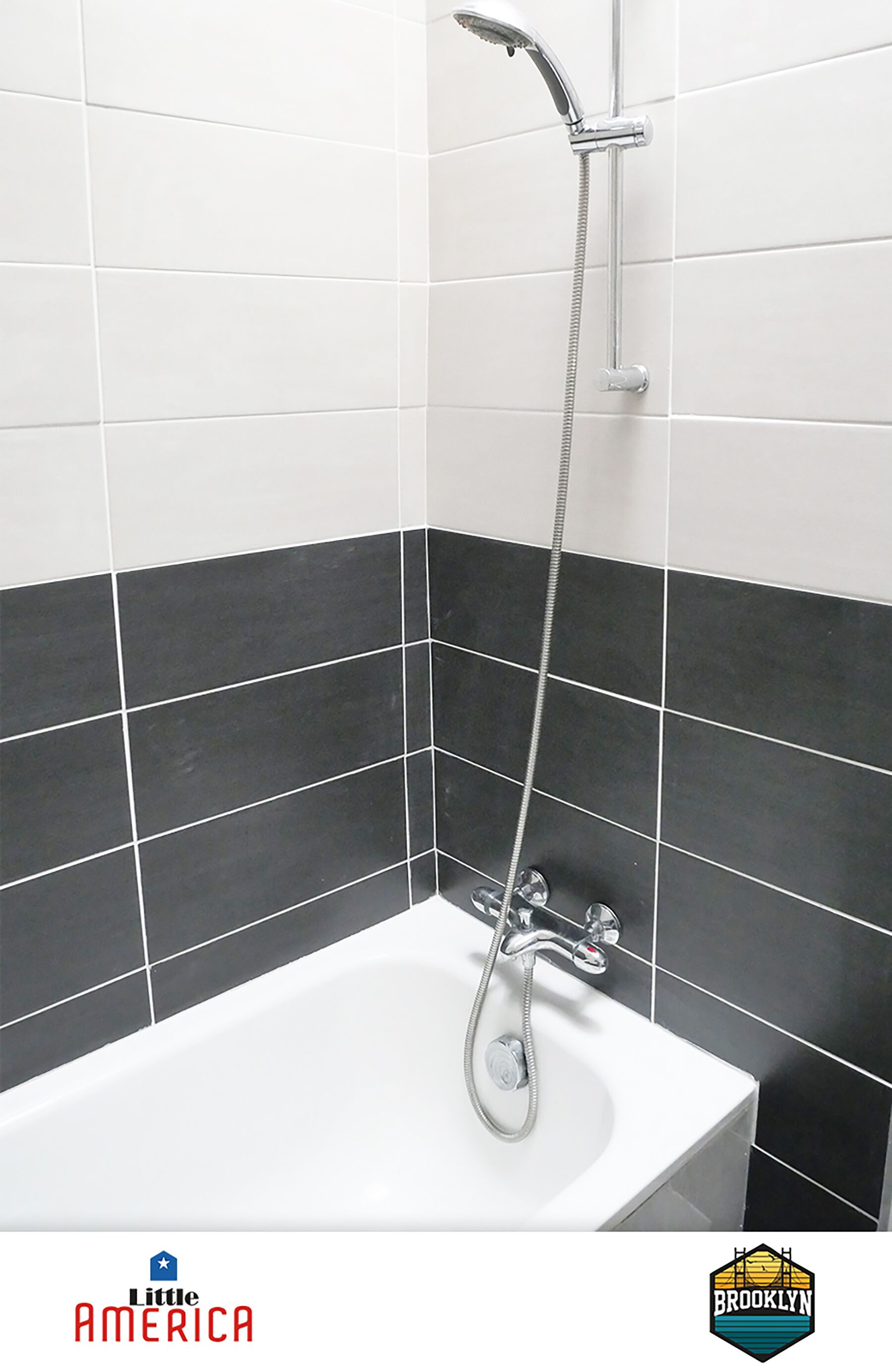 Een badkamer met een wit bad, een douche met een handdouche en zwart-wit betegelde wanden.