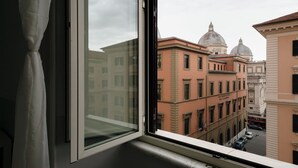 A window with a view of historic buildings, including a building with a dome and another with a row of windows. - DM69 - Termini Monti Crossroads (Rome)