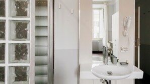 A bathroom with a white sink, a mirror, and a hairdryer mounted on the wall. - DM69 - Termini Monti Crossroads (Rome)