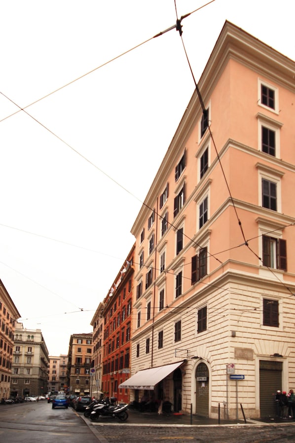 A street view with a building featuring a large arched entrance and a signboard.