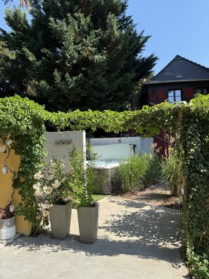 A garden with potted plants, a hot tub, and a house in the background.