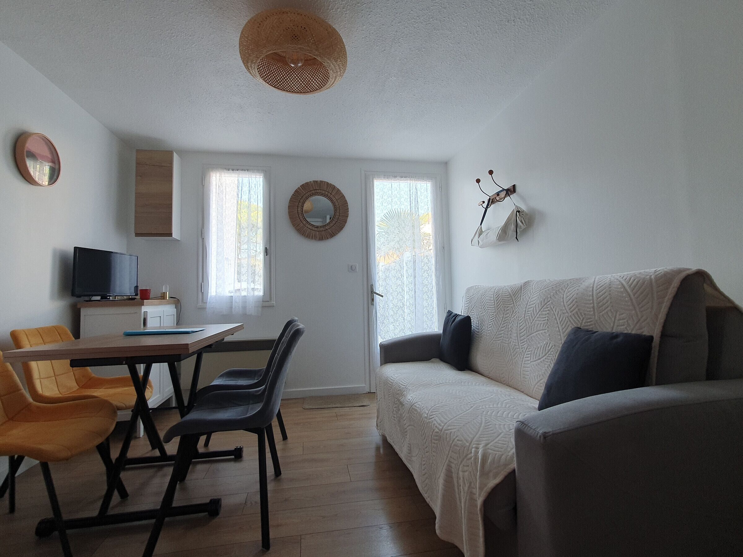 A living room with a sofa, chairs, a dining table, and a television.