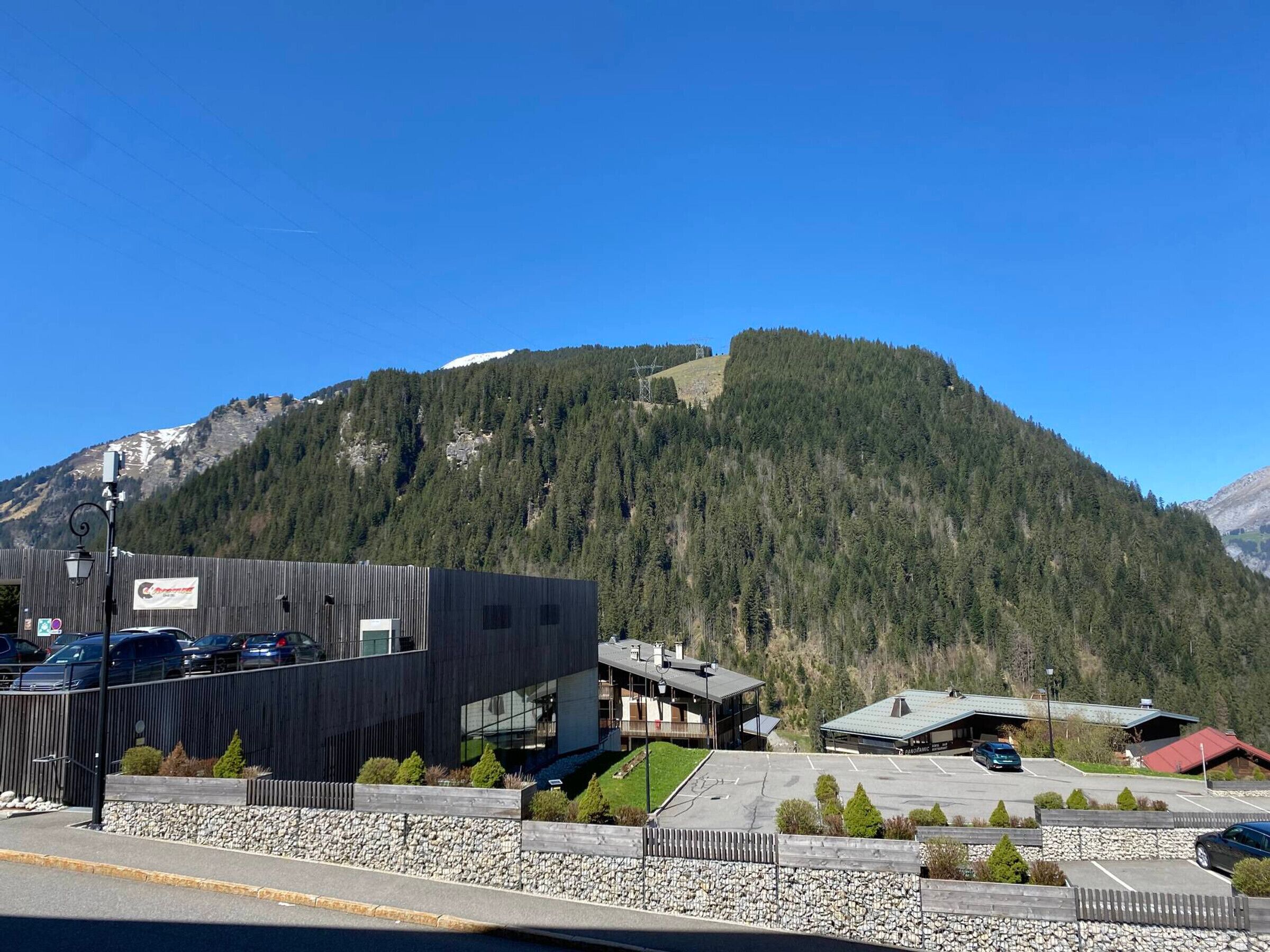 A modern building with a parking lot, surrounded by a mountainous landscape.