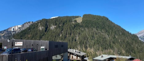 A modern building with a parking lot, surrounded by a mountainous landscape.