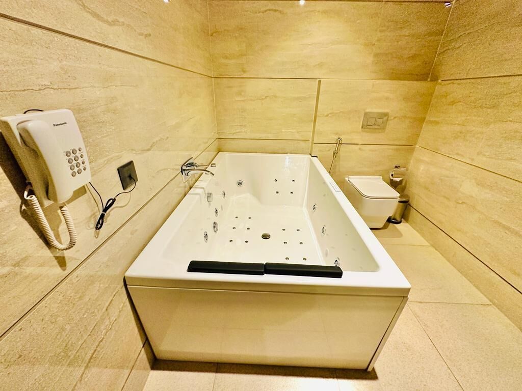 A modern bathroom with a large bathtub, a toilet, and a telephone.