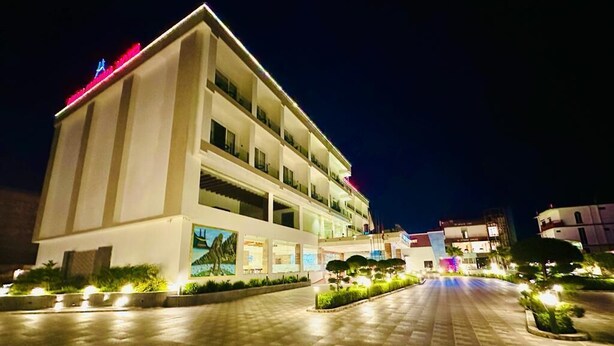 A multi-story hotel with a central courtyard, illuminated by ground lights. - Asian Buddha Hotel (Siddharthanagar)