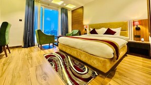 A modern hotel room with a large bed, a desk, and a view of the city. - Asian Buddha Hotel (Siddharthanagar)