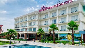 A hotel with a pool, palm trees, and a Buddha statue. - Asian Buddha Hotel (Siddharthanagar)