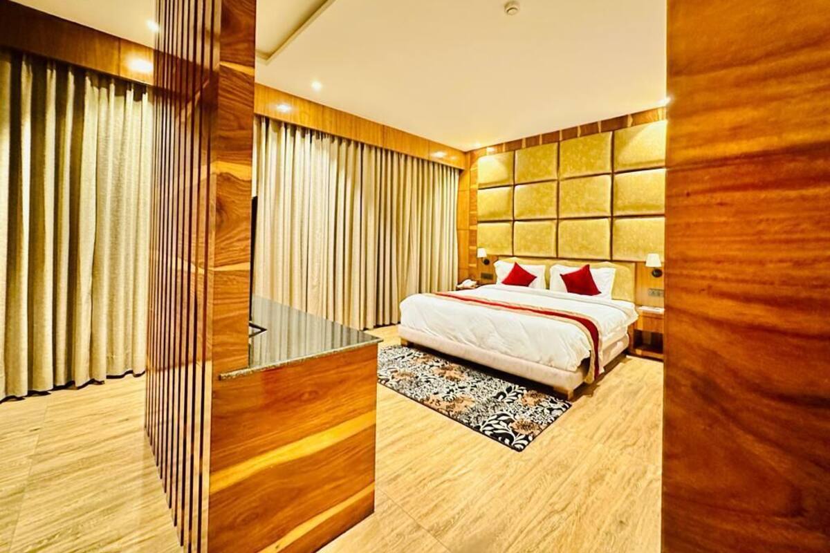 A modern bedroom with a large bed, wooden paneling, and a patterned rug.