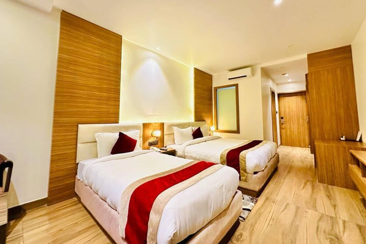 A hotel room with two beds, wooden paneling, a desk, and a mirror.