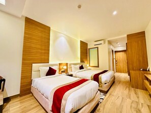 A hotel room with two beds, wooden paneling, a desk, and a mirror. - Asian Buddha Hotel (Siddharthanagar)