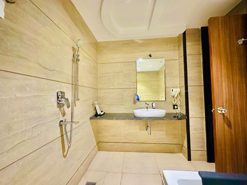 Une salle de bain moderne équipée d’une douche, d’un lavabo et d’un miroir.