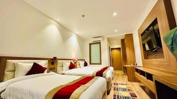 A hotel room with two beds, a TV, a desk, and a small seating area.