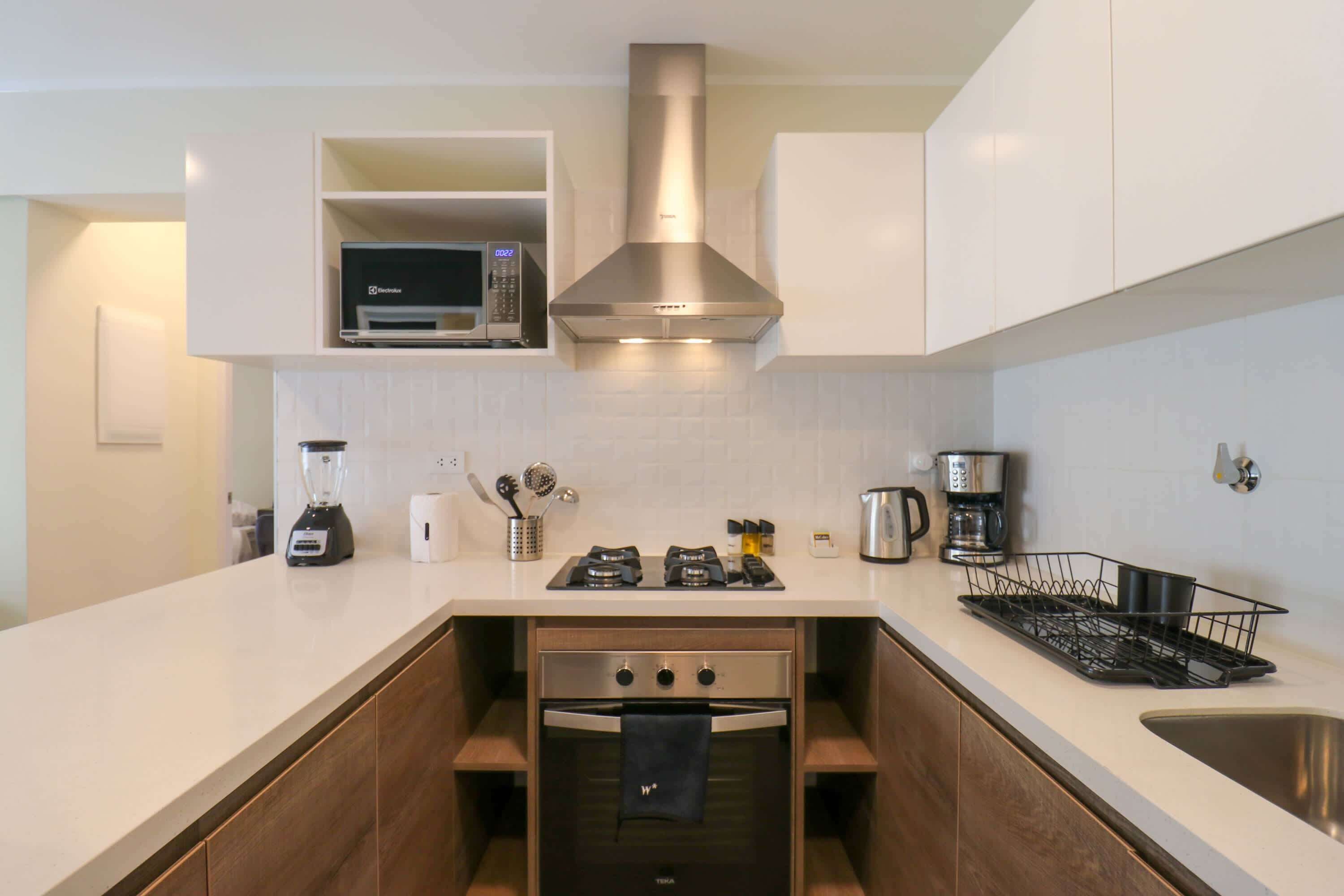 A compact kitchen with a built-in microwave, a gas stove, and a stainless steel range hood.