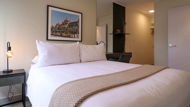 A hotel room with a large bed, a framed picture on the wall, a bedside lamp, and a mirror above the bed. - w* | Spectacular 2BR in the Heart of Miraflores (Miraflores)