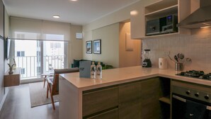 A modern kitchen with a built-in microwave, stove, and a blender on the counter. There is a small island with a seating area and a welcome sign. - w* | Spectacular 2BR in the Heart of Miraflores (Miraflores)