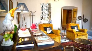 Ein Wohnzimmer mit Sofa, Sesseln, Couchtisch und Lampe.
