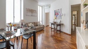 Een moderne woonkamer met een glazen eettafel, houten vloeren en een bank.