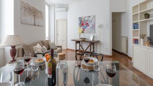 Een eethoek met een tafel gedekt voor twee personen, een bank en een schilderij aan de muur.