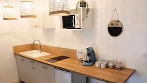 Ett modernt kök med en bänkskiva i trä, vita skåp, en inbyggd diskmaskin, en kaffebryggare och en skylt med Wi-Fi-lösenordet.
