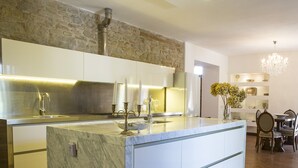 A modern kitchen with a marble island, stainless steel appliances, and a stone accent wall. - Villa San Marco - Homelike Villas (Torre San Marco)