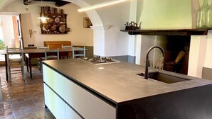 A modern kitchen with a central island, a built-in sink, and a stove. - Villa San Giglio - Homelike Villas (Foligno)