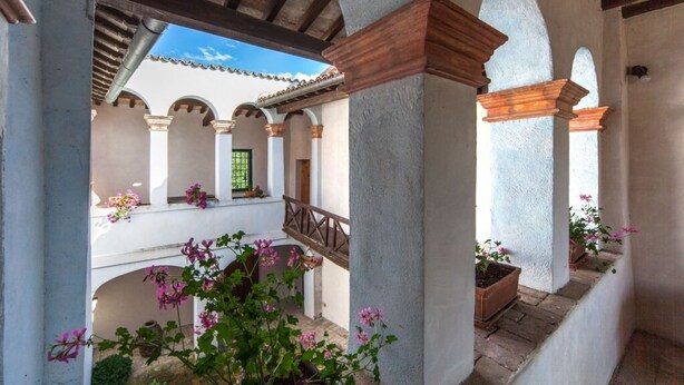 A covered courtyard with arches, potted plants, and a wooden railing. - Villa San Giglio - Homelike Villas (Foligno)